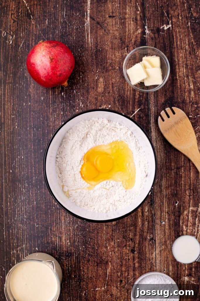 Mixing bowl filled with flour and cracked eggs in the center, surrounded by butter, milk, and other ingredients for making eggnog crepes, demonstrating the initial setup.
