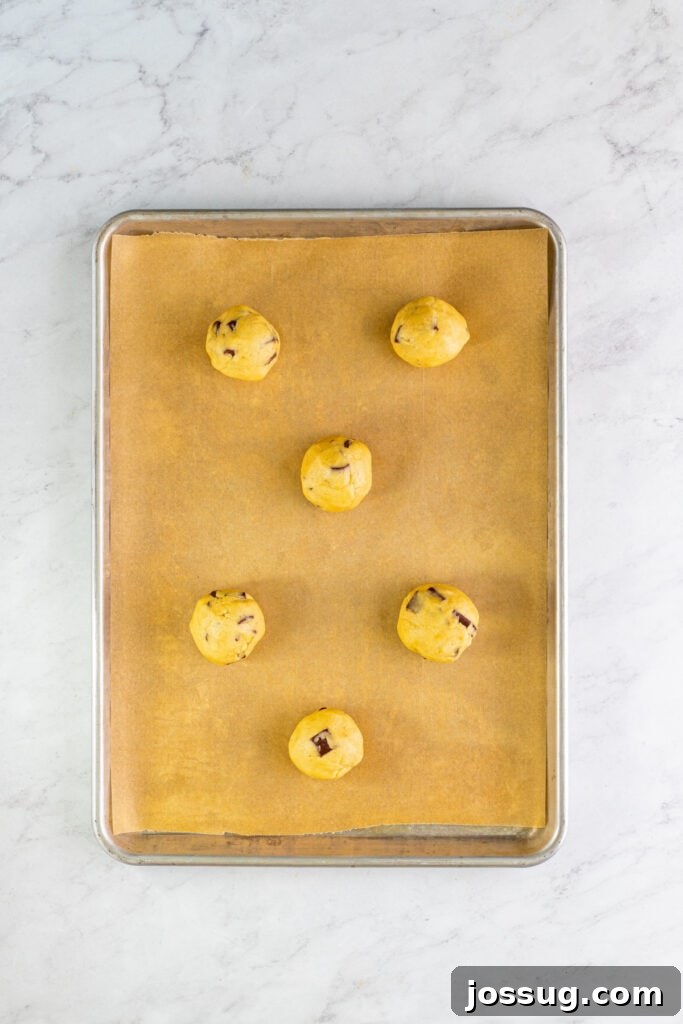 Evenly spaced cookie dough balls arranged on a parchment-lined baking sheet, prepared for baking.