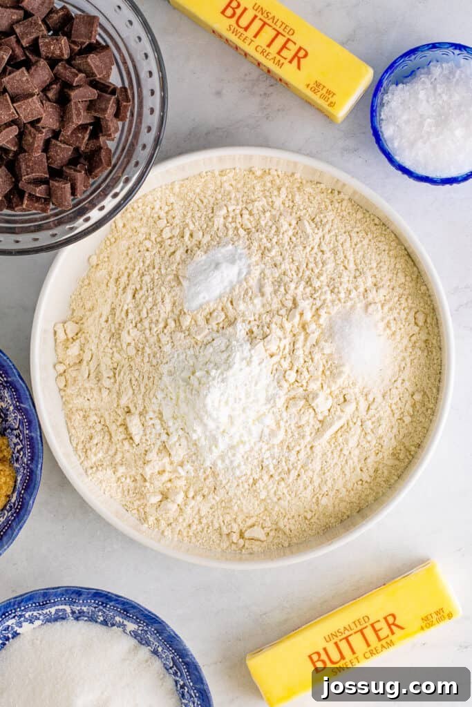Large bowl containing flour mixture with cornstarch, baking soda, and fine sea salt on top, ready for whisking.
