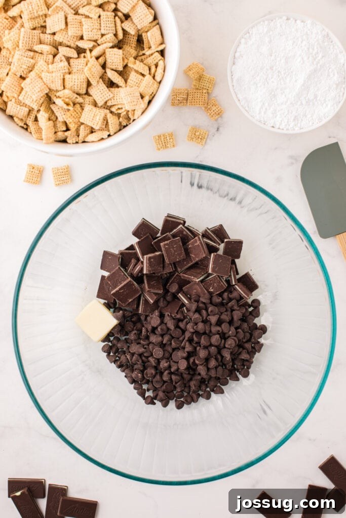 Large glass bowl filled with chocolate chips, chopped Andes mints, and a piece of butter before melting.