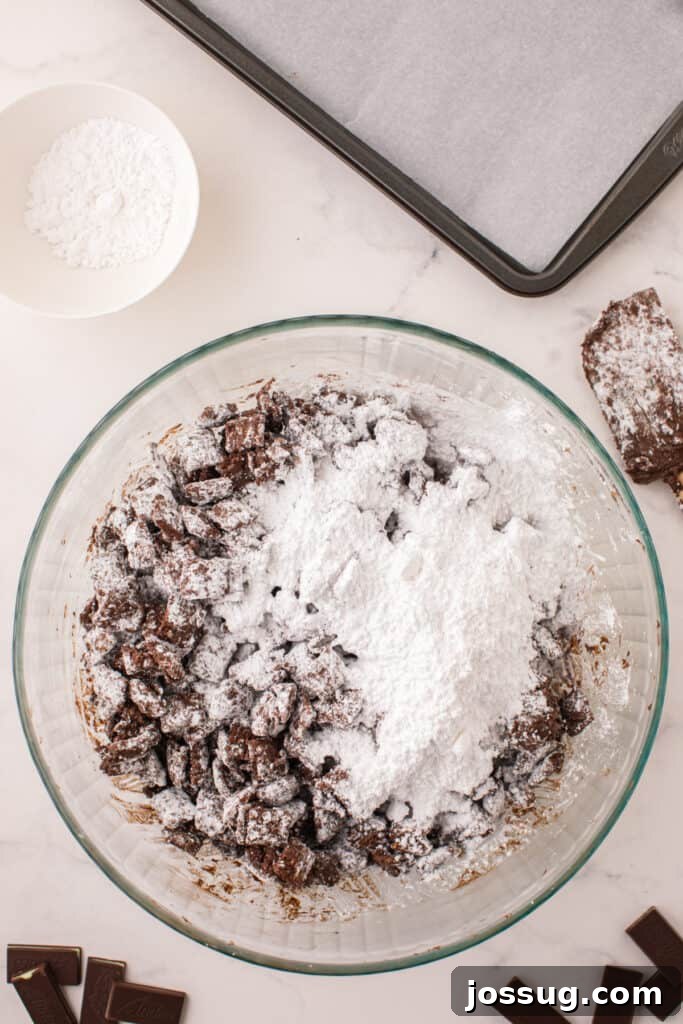 Half mixed bowl of powdered sugar and chocolate coated cereal showing the coating process.
