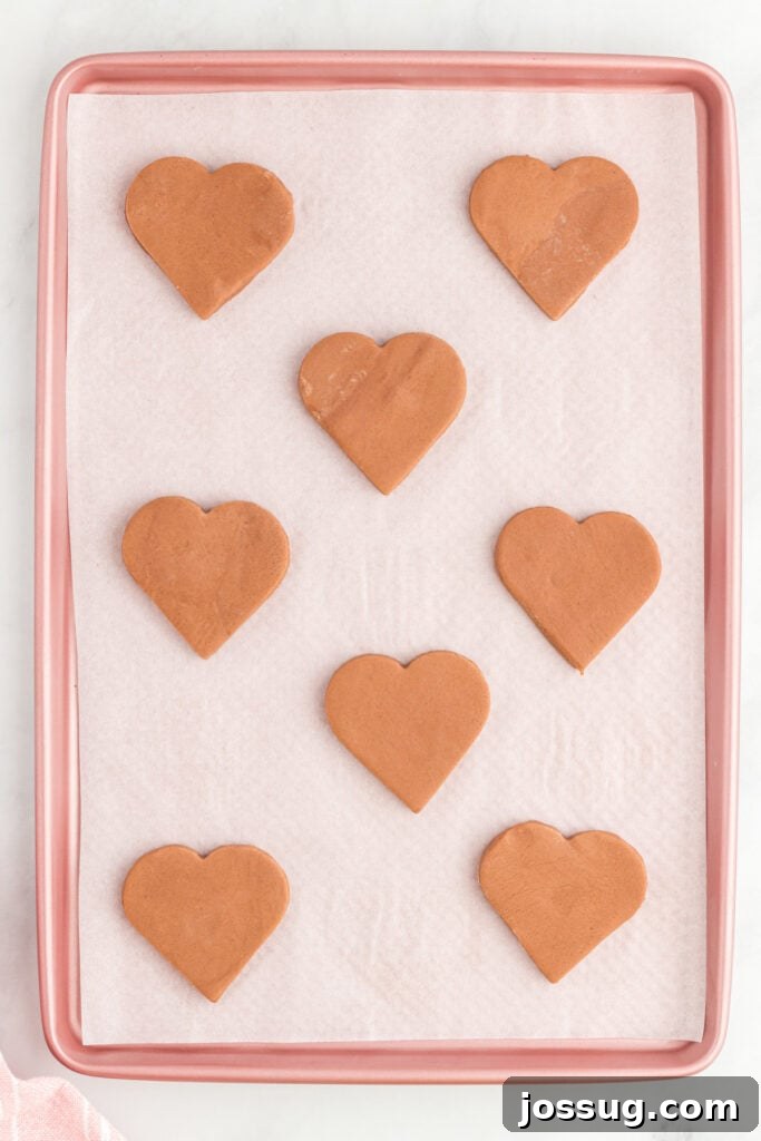 Unbaked heart-shaped chocolate cookies on a baking sheet.