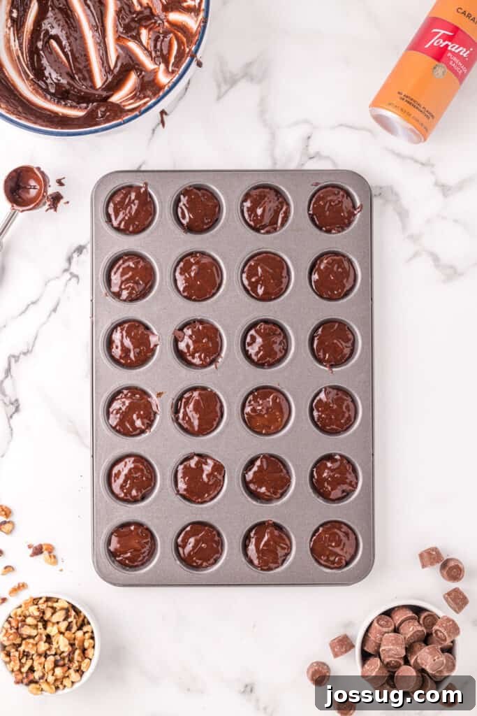 Mini muffin pan filled with spooned brownie batter, shown alongside the mixing bowl, scoop, walnuts, and Rolos.