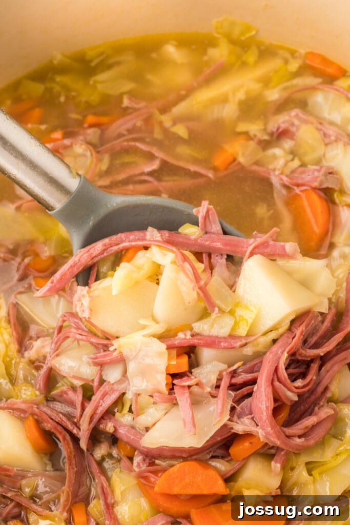 Hearty Corned Beef and Cabbage Soup 4 A ladle serving a portion of rich corned beef and cabbage soup from a large pot.