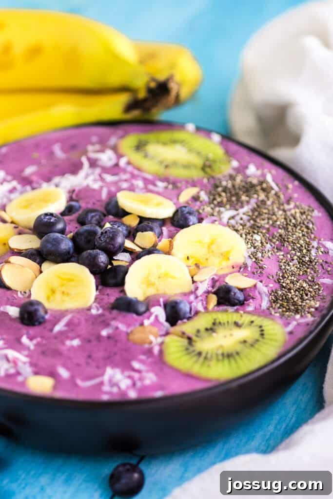A beautifully garnished blueberry banana smoothie bowl, featuring various fruits and chia seeds.