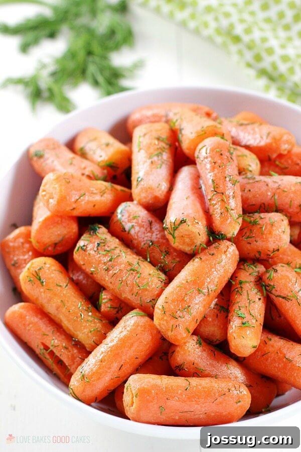 A close-up view of tender Dill Butter Carrots, highlighting their glistening butter coating and finely chopped dill in a white bowl.