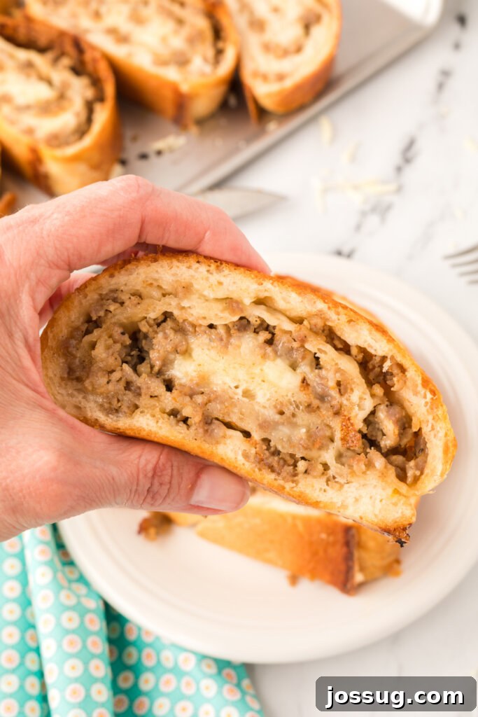 Hand holding a slice of golden-brown sausage bread, showcasing the cheesy, savory filling.