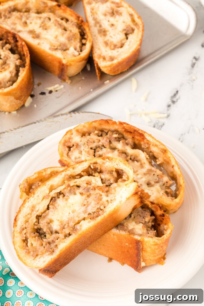 Slices of baked sausage bread arranged neatly on a plate, showing the spiral layers of dough, sausage, and cheese.