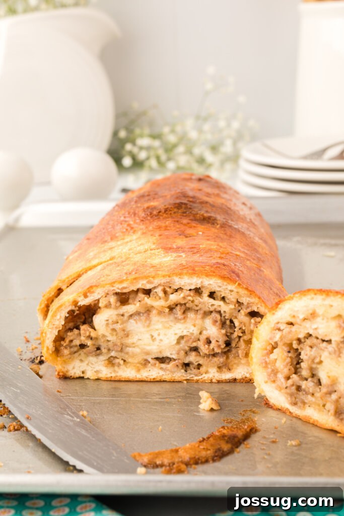 Freshly baked sausage bread cooling on a baking sheet, showcasing its golden crust and delicious form.