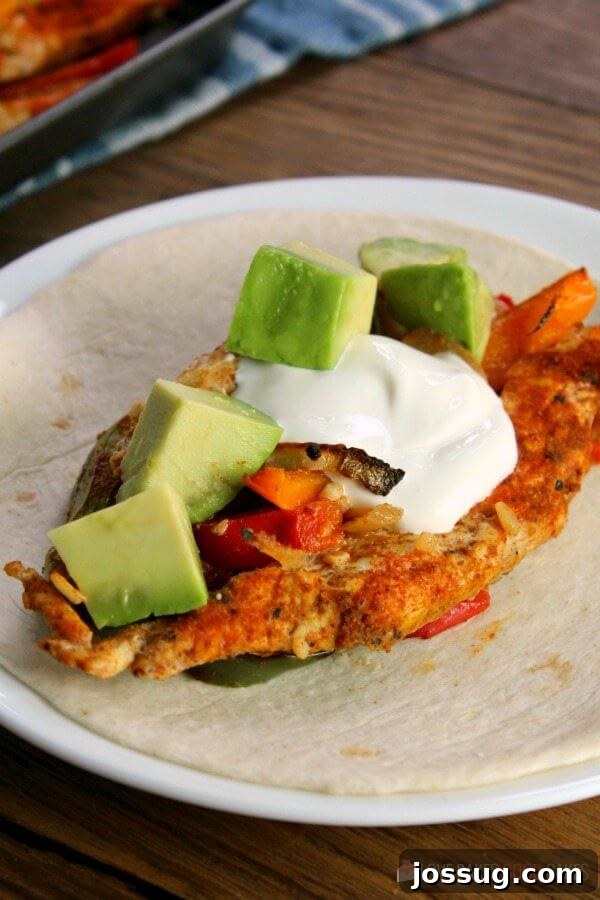 A single portion of Sheet Pan Chicken Fajitas nestled in a warm flour tortilla.