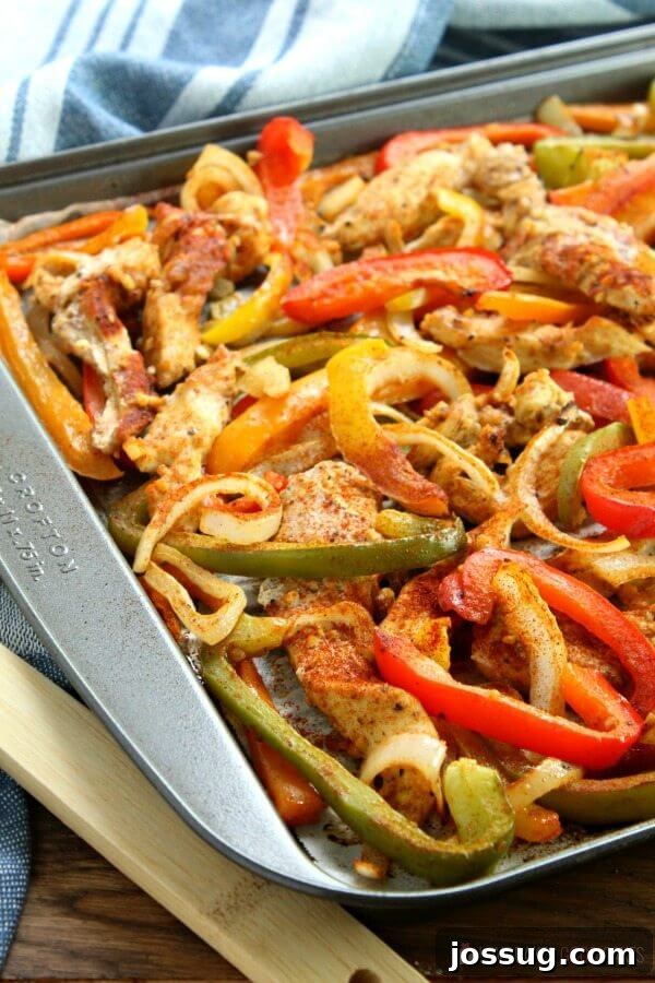 A baking sheet filled with freshly roasted Sheet Pan Chicken Fajitas, ready to be dressed.