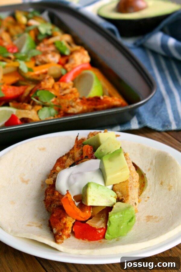 A close-up of a Sheet Pan Chicken Fajita in a flour tortilla with toppings.