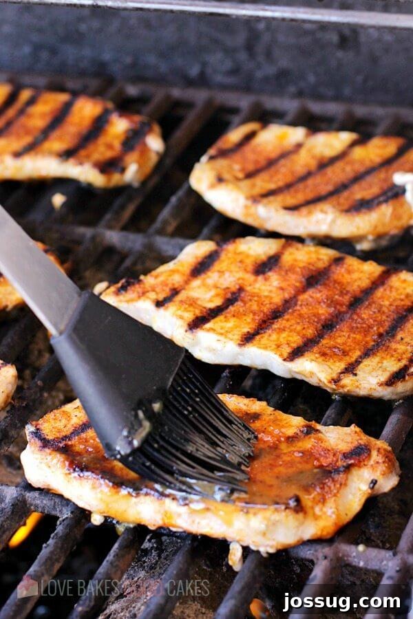 Tangy Peach Glazed Pork Chops 3 Dijon-Peach Pork Chops cooking on a hot grill, being basted with the flavorful glaze.