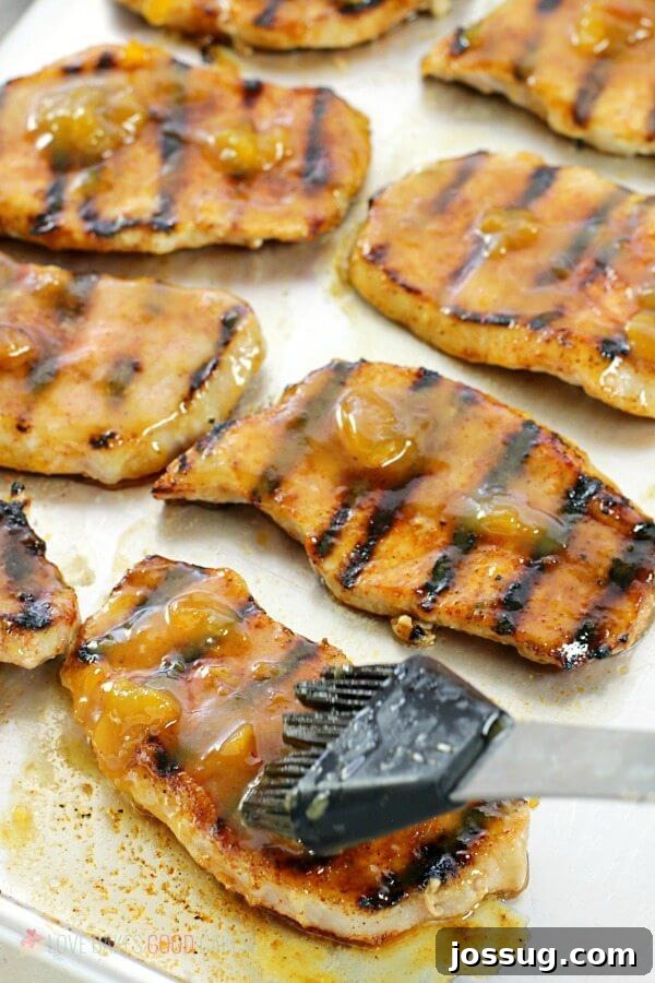 Tangy Peach Glazed Pork Chops 4 Close-up of boneless pork chops being basted with a rich dijon-peach glaze while on the grill.