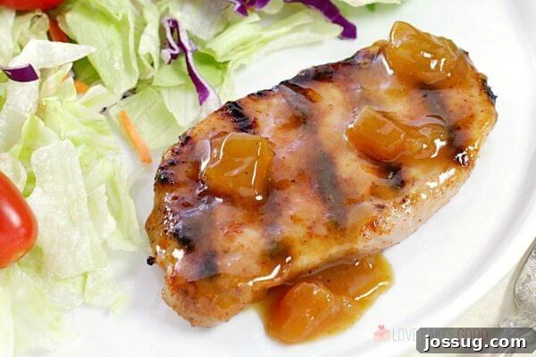 Tangy Peach Glazed Pork Chops 6 Close-up of a Dijon-Peach Pork Chop on a plate, showcasing the caramelized glaze and tender meat, served with a side salad.