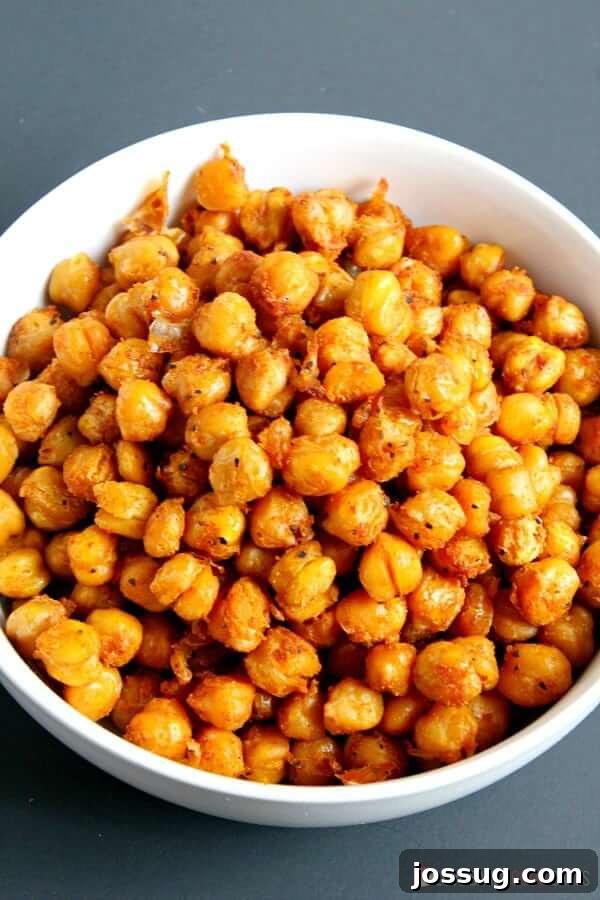 A white bowl filled with golden-brown spicy roasted chickpeas, ready for a healthy snack.