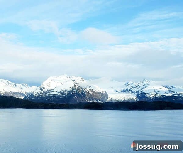 Last-Minute Cruises: Sail Sooner, Save More 4 A serene body of water reflecting snow-covered mountains under a vast sky, embodying the tranquility of a cruise destination.
