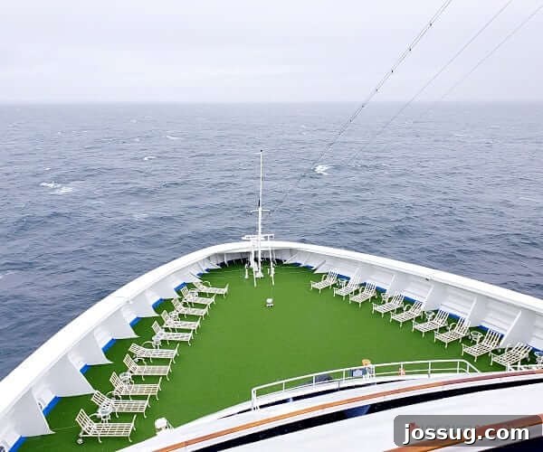Last-Minute Cruises: Sail Sooner, Save More 7 The spacious bow deck of a cruise ship, adorned with comfortable lounger chairs, inviting passengers to relax and enjoy the sea breeze.