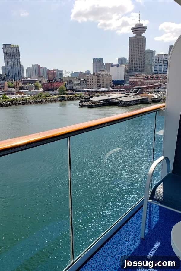 An expansive view from a private cruise ship balcony looking down towards the impressive skyline of a large city at port, showcasing the privacy and elevated perspective a balcony room offers.