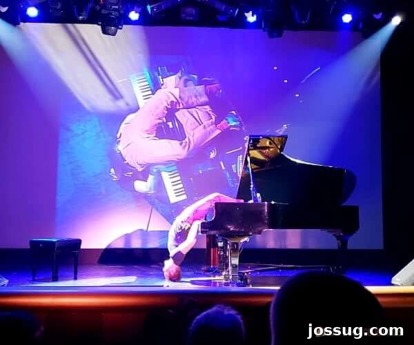 A talented man playing a piano upside down on stage in the grand theater of a cruise ship, captivating the audience.