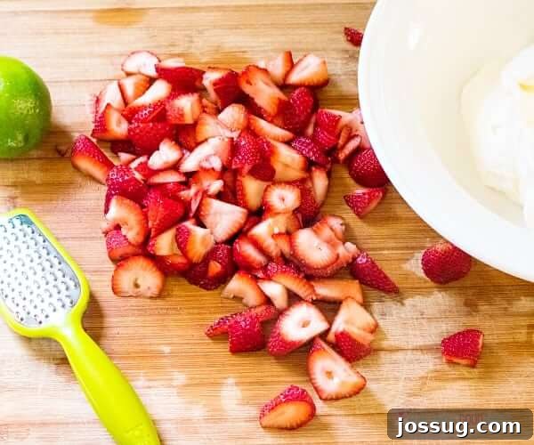 Tipsy Strawberry Margarita Poke Cake 4 Fresh strawberries sliced on a cutting board, ready for the margarita poke cake.