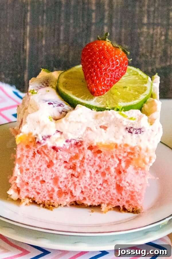 Tipsy Strawberry Margarita Poke Cake 5 A perfectly portioned slice of Boozy Strawberry Margarita Poke Cake, garnished with fresh lime and strawberry.