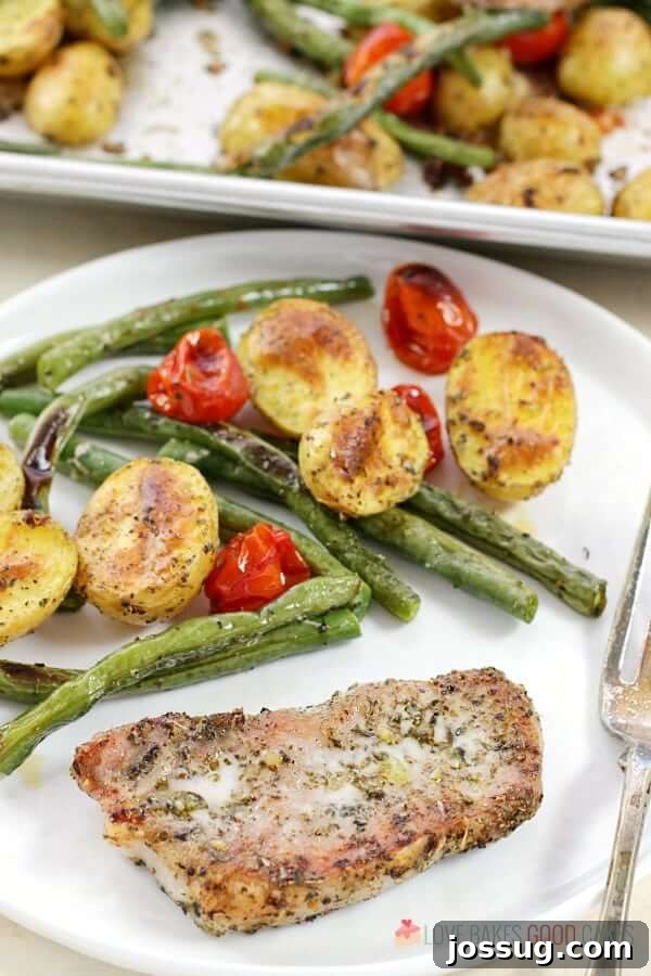 A perfectly cooked Italian Pork Chop Sheet Pan Dinner served on a white plate with a fork, showcasing crispy pork, golden potatoes, and vibrant vegetables.