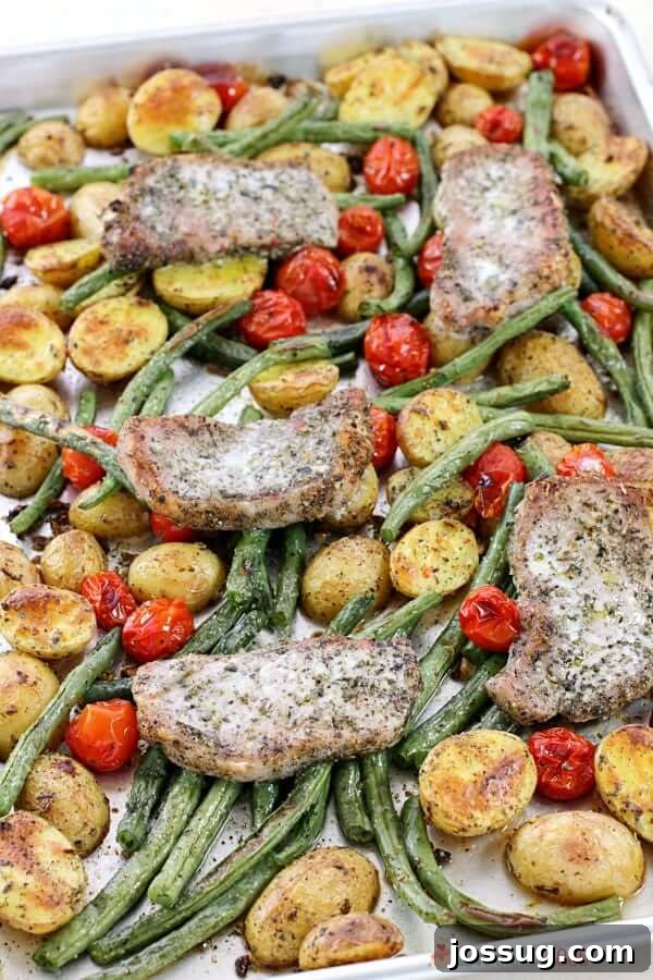 Close-up of the Italian Pork Chop Sheet Pan Dinner, still on the baking sheet, showing the rustic charm of roasted pork, potatoes, green beans, and tomatoes.