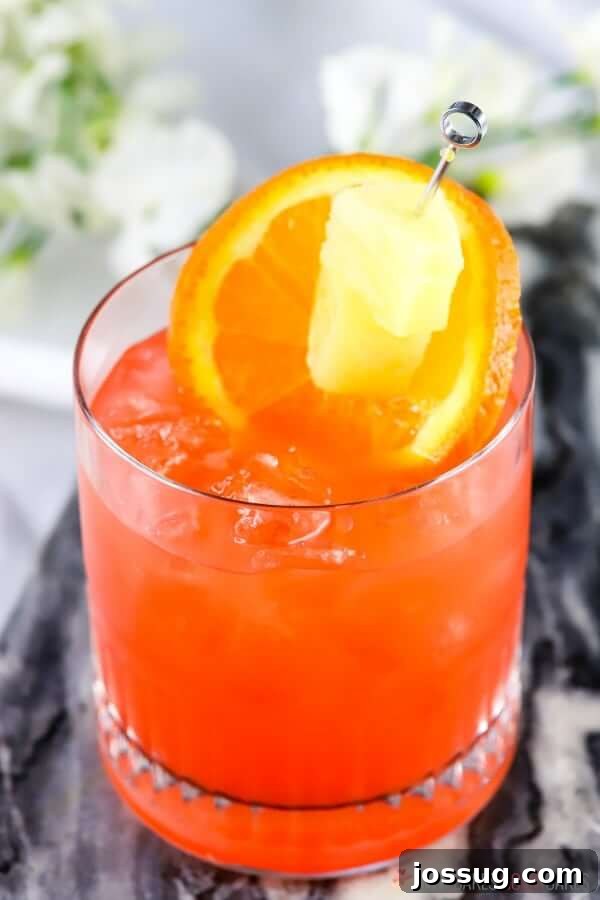Golden Orange Pineapple Rum Delight 2 Vibrant Orange and Pineapple Rum Punch in a glass, garnished with fresh fruit, on a sunny outdoor setting.