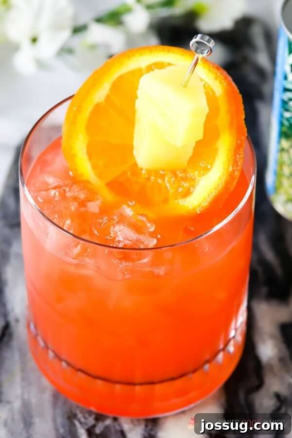 Golden Orange Pineapple Rum Delight 3 Close-up of Orange and Pineapple Rum Punch in a glass, showcasing the refreshing ice and fruit.