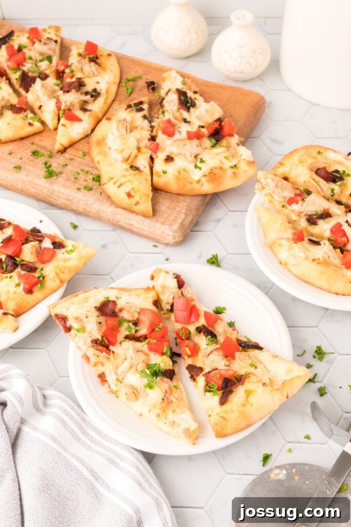 Two slices of Chicken Bacon Ranch Naan Bread Pizza on a white plate, ready to eat.