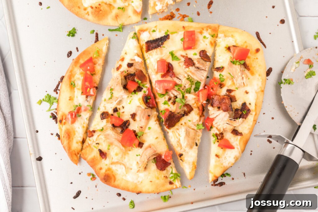 Looking down onto a chicken bacon ranch naan bread pizza cut into slices, perfect for sharing.