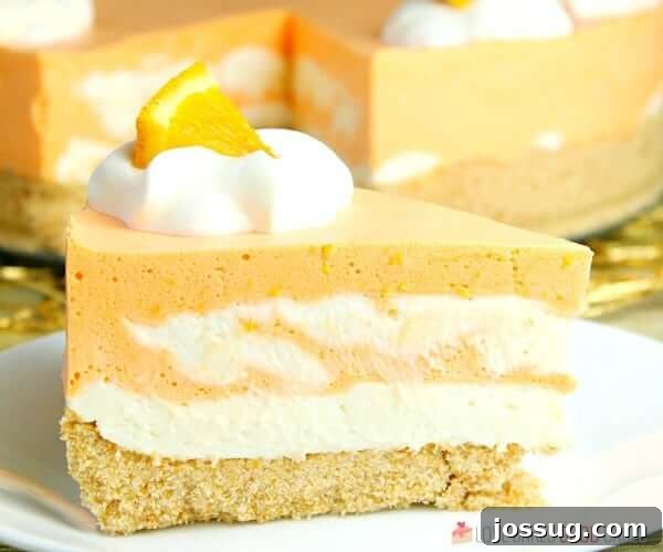 A close-up of a slice of No-Bake Orange Creamsicle Cheesecake on a plate, highlighting the creamy layers.