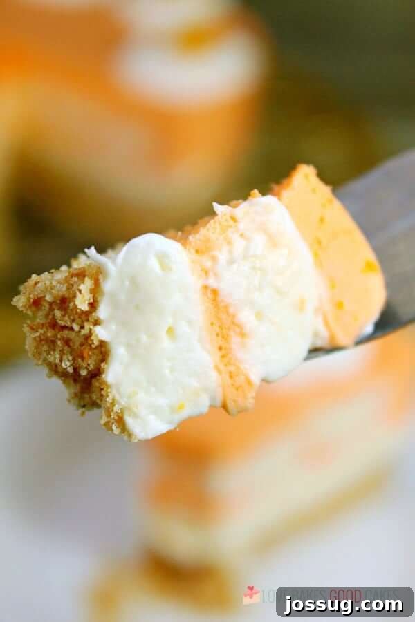 A small piece of No-Bake Orange Creamsicle Cheesecake on a spoon, ready to be enjoyed.