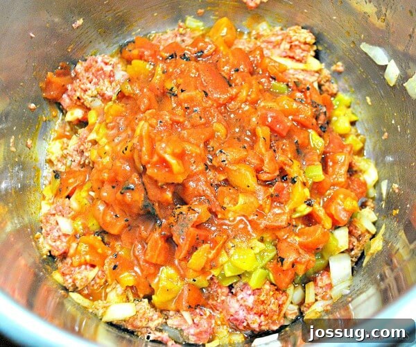 Ultimate Instant Pot Mexican Queso Dip 5 Instant Pot Mexican Queso being vigorously stirred in a metal bowl after cooking, showing its smooth, creamy texture and integrated ingredients. A large mixing spoon is actively working through the dip.