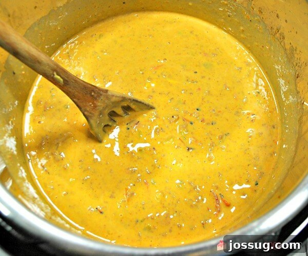 Ultimate Instant Pot Mexican Queso Dip 7 Another view of Instant Pot Mexican Queso being stirred in a large metal bowl, highlighting its perfect readiness and inviting texture for serving at any gathering.