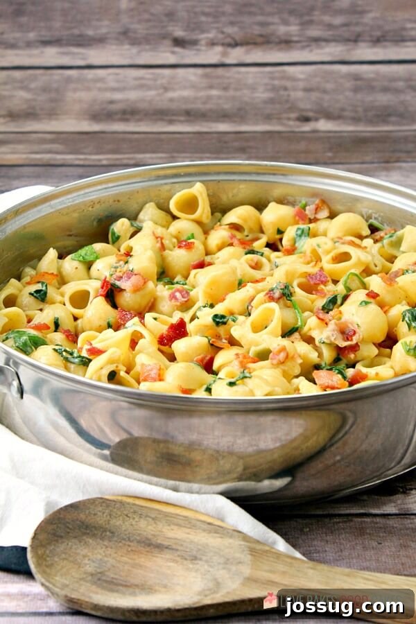 Effortless Creamy Bacon Spinach One-Pot Pasta 3 One-Pot Creamy Bacon Spinach Pasta in a skillet, ready to be served, with a spoon resting in it.