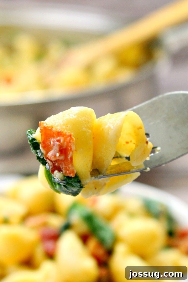 Effortless Creamy Bacon Spinach One-Pot Pasta 7 A fork lifting a mouthful of One-Pot Creamy Bacon Spinach Pasta, close-up, showing the creamy sauce, bacon, and spinach.
