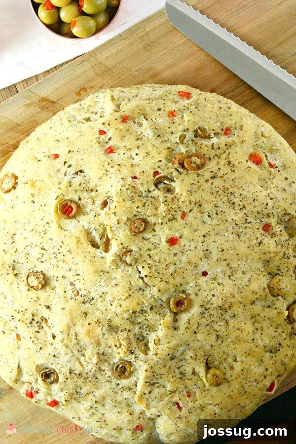 Sliced No-Knead Skillet Olive Bread with a knife on a cutting board, ready for serving.