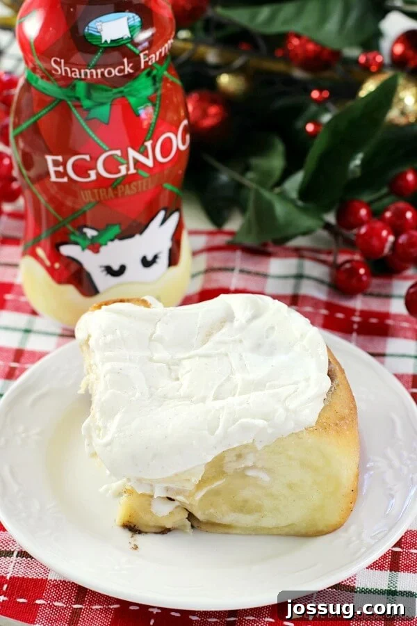 Festive Eggnog Cinnamon Rolls 2 A perfectly frosted Eggnog Cinnamon Roll on a white plate, with a festive glass bottle of Shamrock Farms Eggnog slightly blurred in the background, hinting at holiday cheer and indulgence.