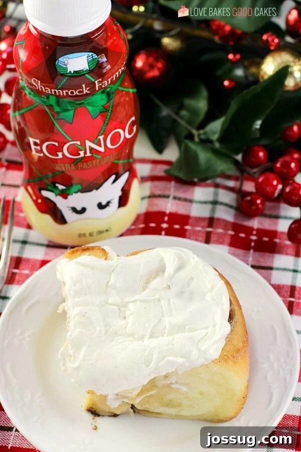 Festive Eggnog Cinnamon Rolls 4 Three perfectly risen and frosted Eggnog Cinnamon Rolls beautifully arranged on a plate, with a blurred festive bottle of Shamrock Farms Eggnog in the background, setting a cheerful holiday scene.