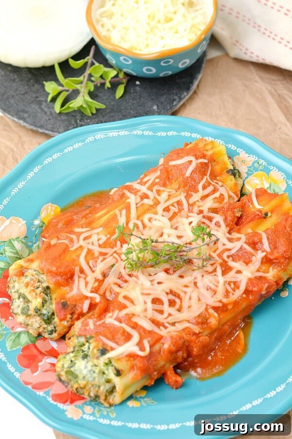 Spinach Ricotta Manicotti on a blue plate, garnished with fresh herbs.