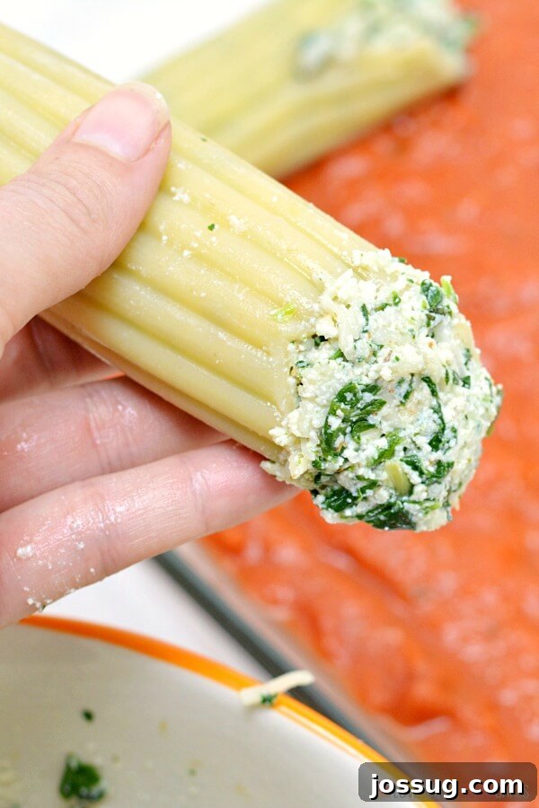 Manicotti shells stuffed with spinach ricotta cheese mixture, lined up in a baking dish.