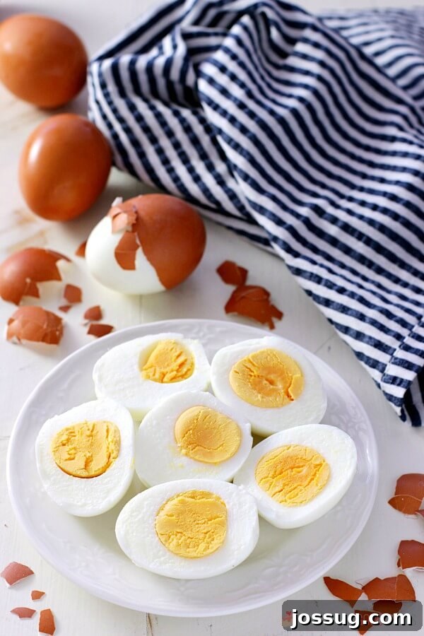 Perfect hard-boiled eggs on a white plate, showcasing a vibrant yellow yolk and smooth white.