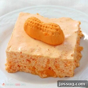 A vibrant, creamy orange Circus Peanut Jello Salad, garnished with whole Circus Peanuts, ready to be served at a gathering.