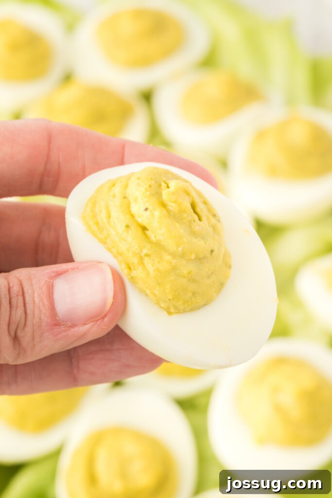 hand holding a pesto deviled egg over other pest deviled eggs