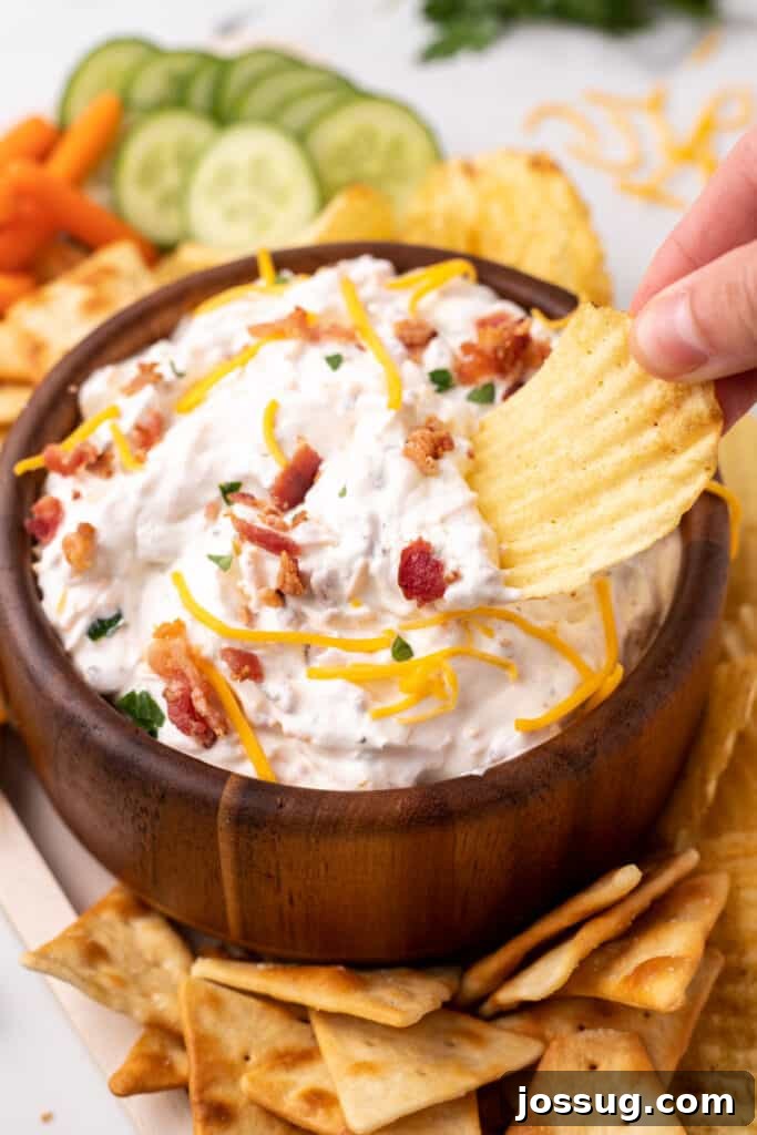 The Gourmet Gala Dip 5 A potato chip scooping a generous amount of creamy Million Dollar Dip.