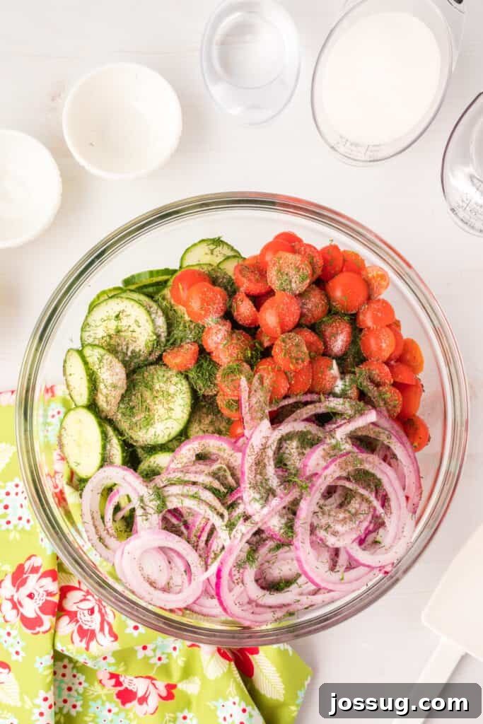 Vibrant Cucumber Tomato Medley 5 The prepped salad ingredients nestled in a spacious glass bowl, lightly seasoned with fresh dill, salt, and celery seed, awaiting the zesty dressing.