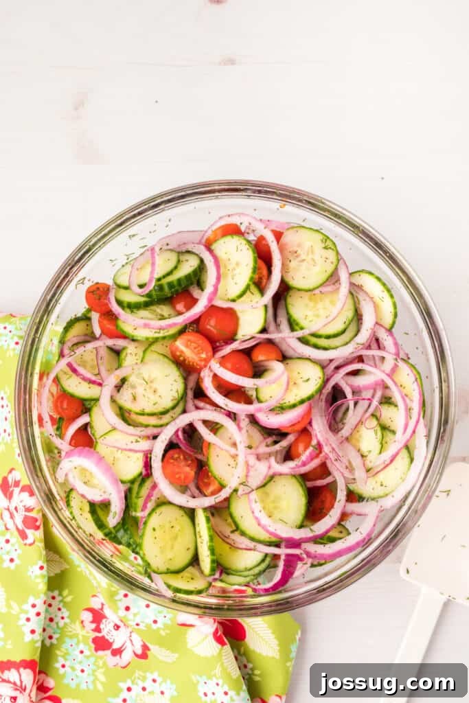 Vibrant Cucumber Tomato Medley 7 The finished Zesty Cucumber Tomato Salad, beautifully tossed with red onions and fresh herbs, presented in a large, inviting glass bowl, ready to be chilled and served.