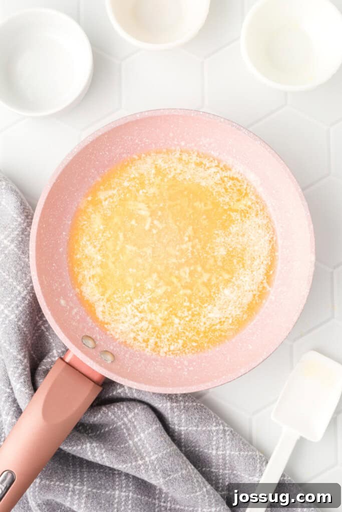 Minced garlic being added to the melted butter in a small pan, infusing it with aromatic flavor for the lemon garlic dipping sauce.